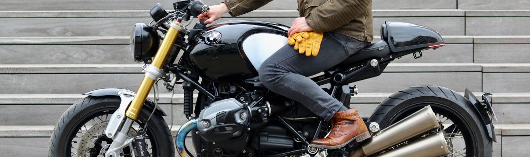 Jeune motard en tenue, heureux de débuter sur sa première moto, prêt à s’équiper pour rouler en sécurité.